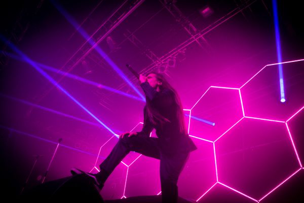 Eurobeat singer Kaioh performing on a large concert stage with pink honeycomb-shaped light installation behind his back